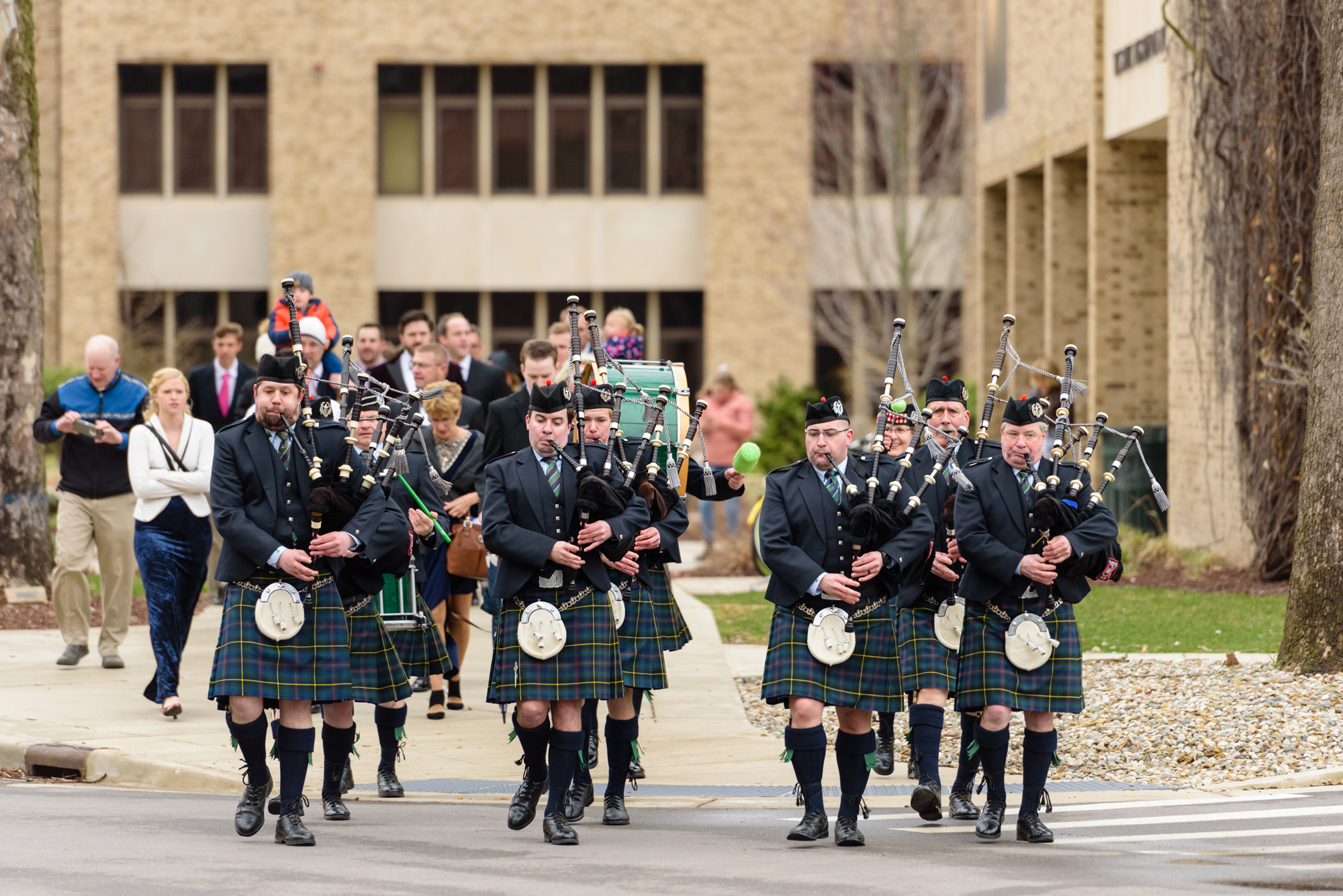 Caledonia Kilty Band bag piper band lead wedding guests to the reception on the campus of University of Notre Dame