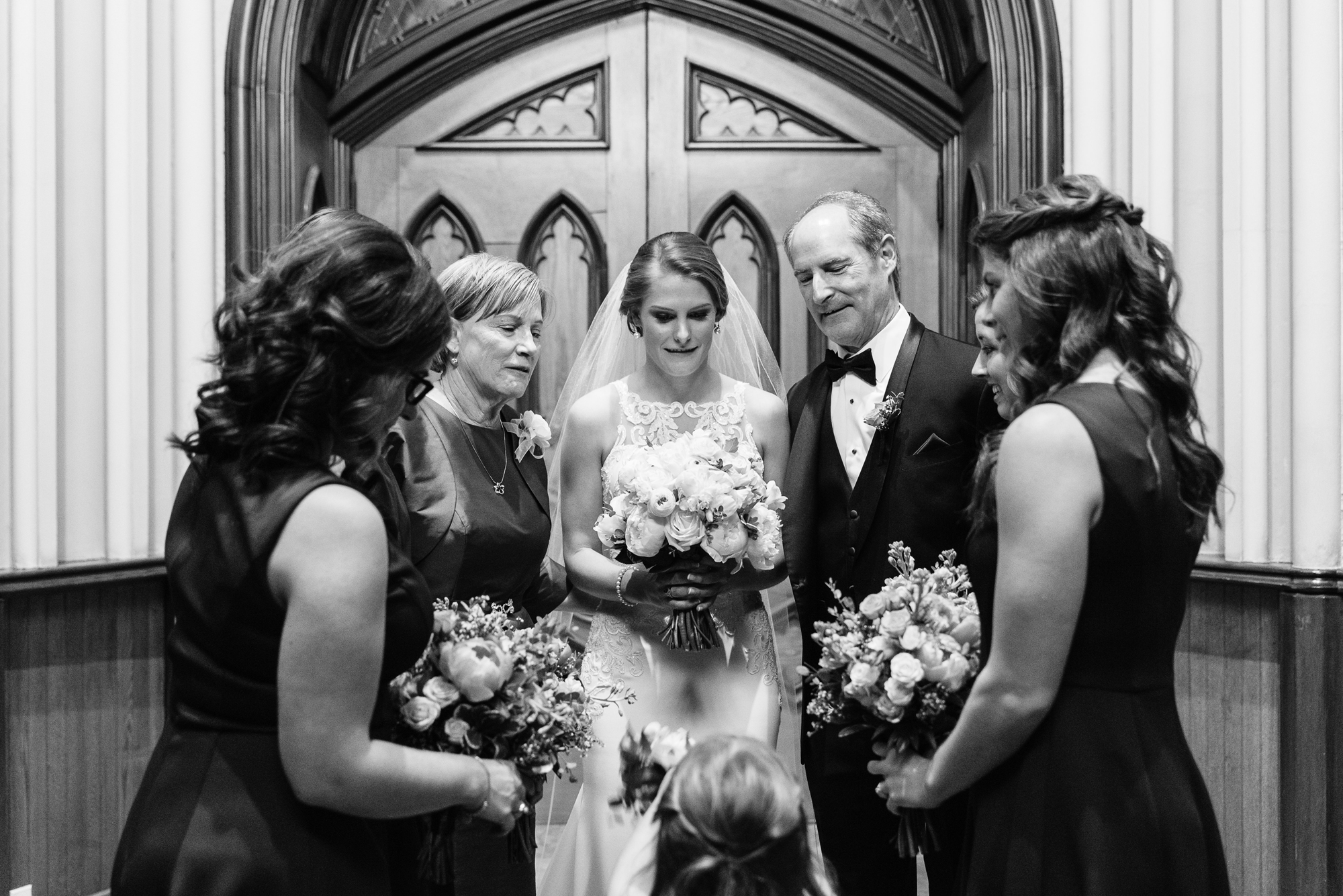 Bride praying with her parents and bridesmaid before her ceremony at the Basilica