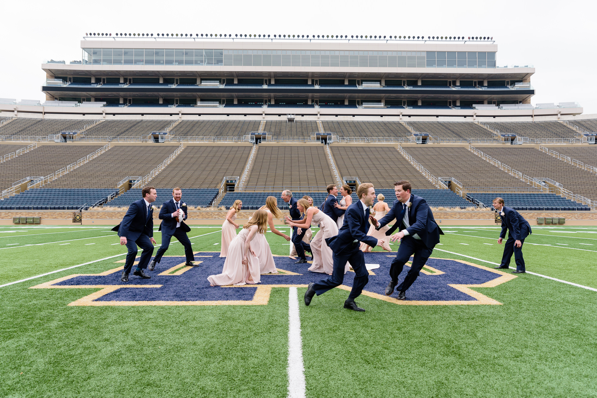 Bridal Party playing football on the field of Notre Dame football stadium