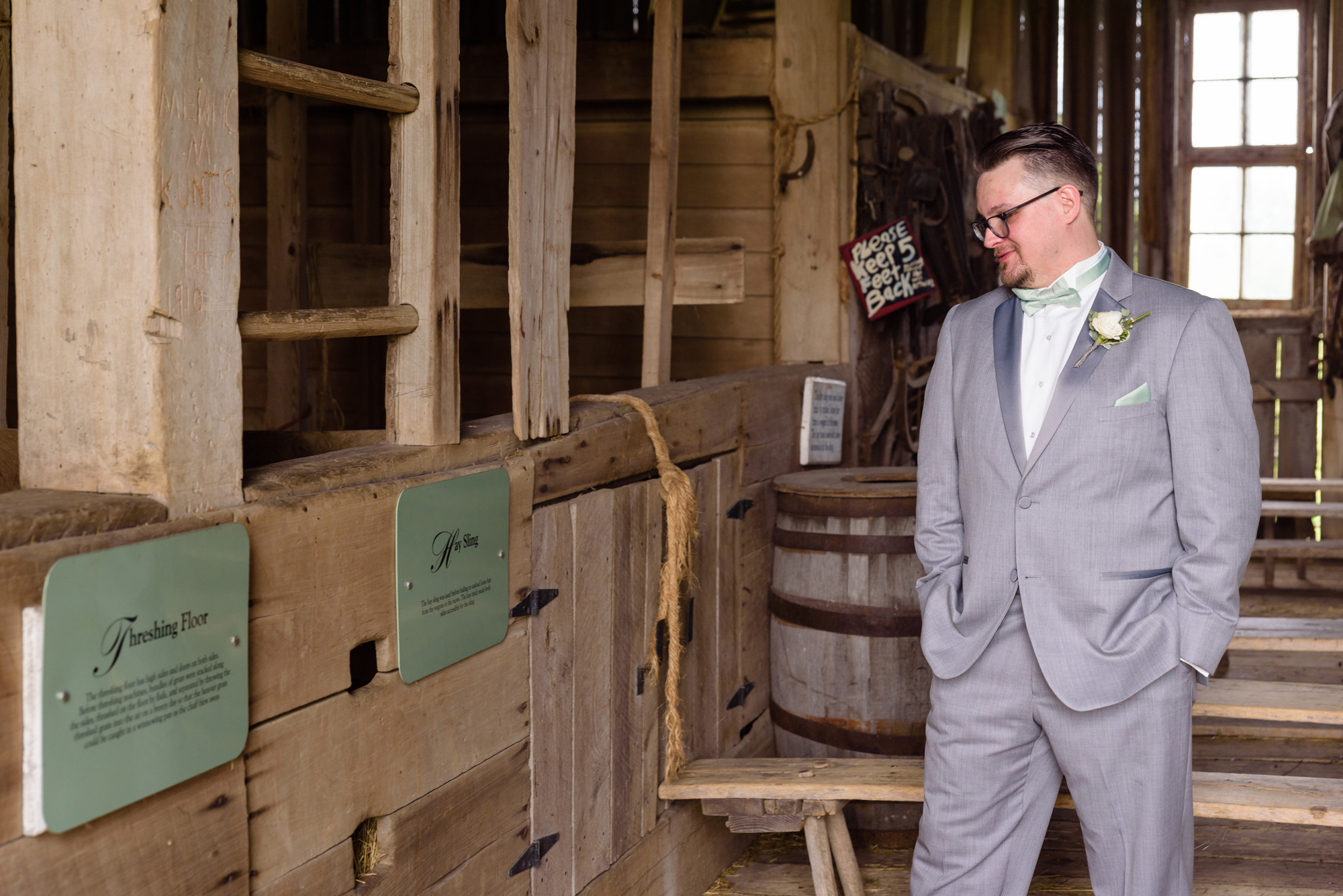 Groom reading a sign in the barn before his wedding at Amish Acres
