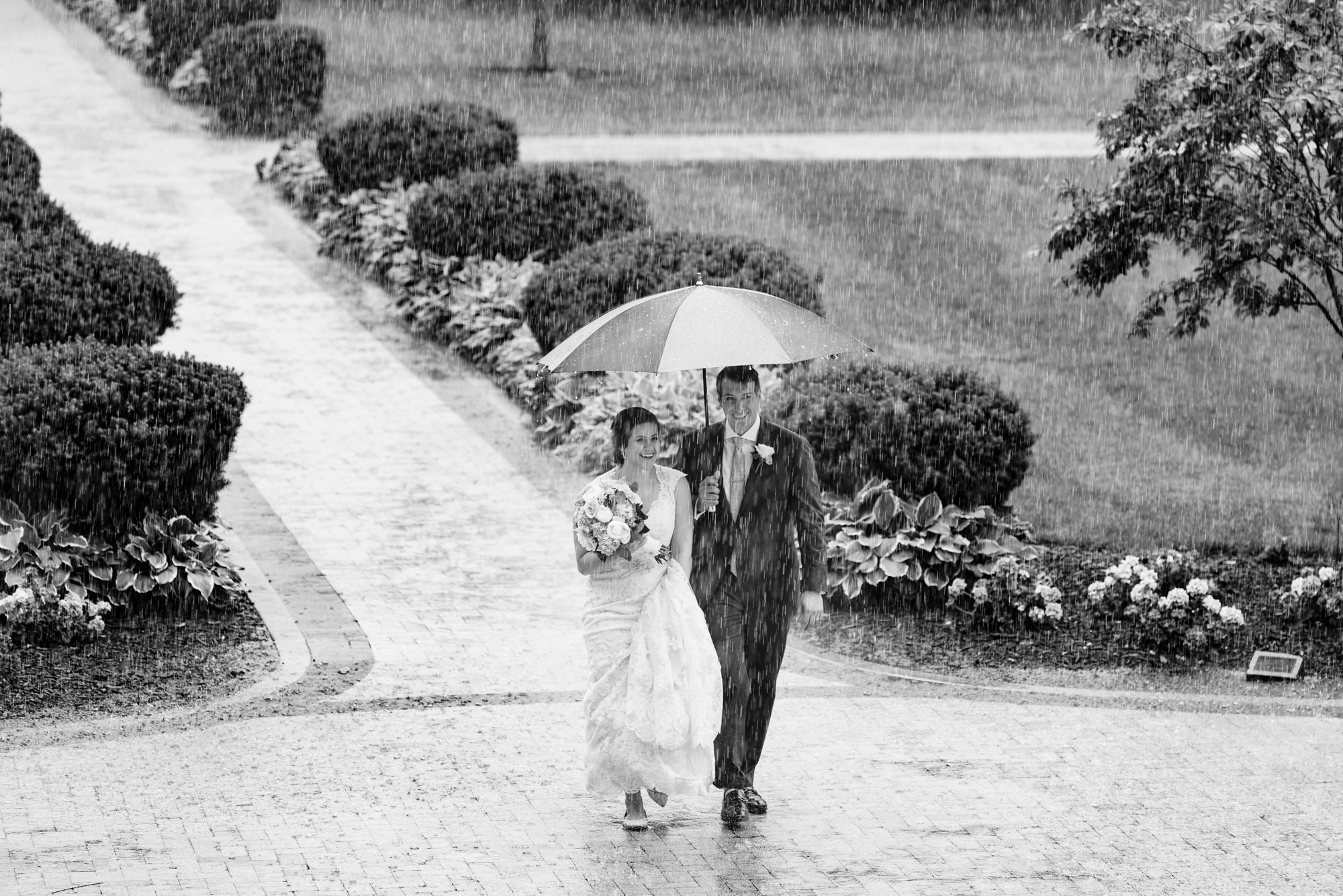 Bride & Groom walking in the rain on God Quad wedding ceremony at the Basilica of the Sacred Heart on the campus of University of Notre Dame