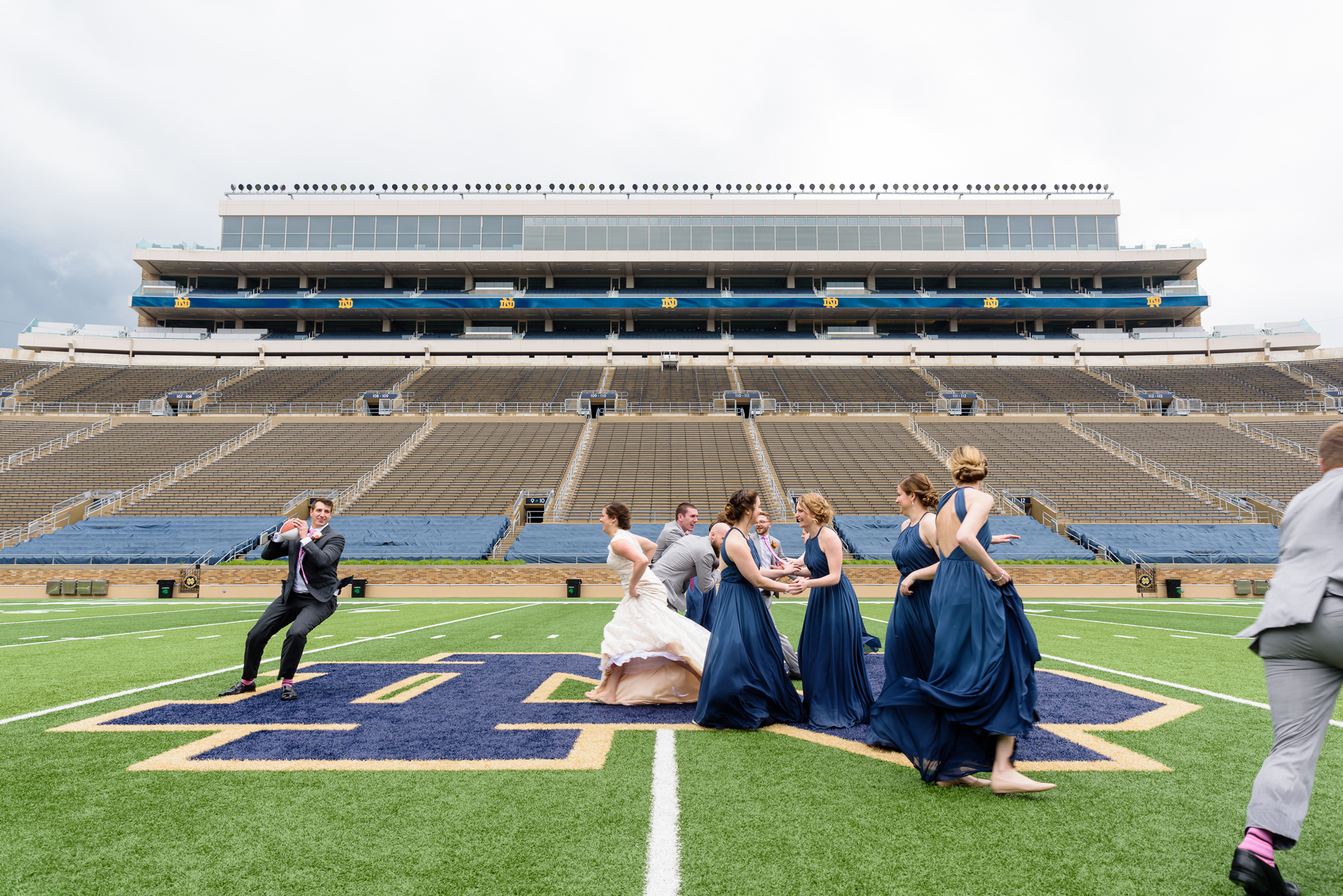 Bridal Party playing football in the stadium after their wedding ceremony at the Basilica of the Sacred Heart on the campus of University of Notre Dame