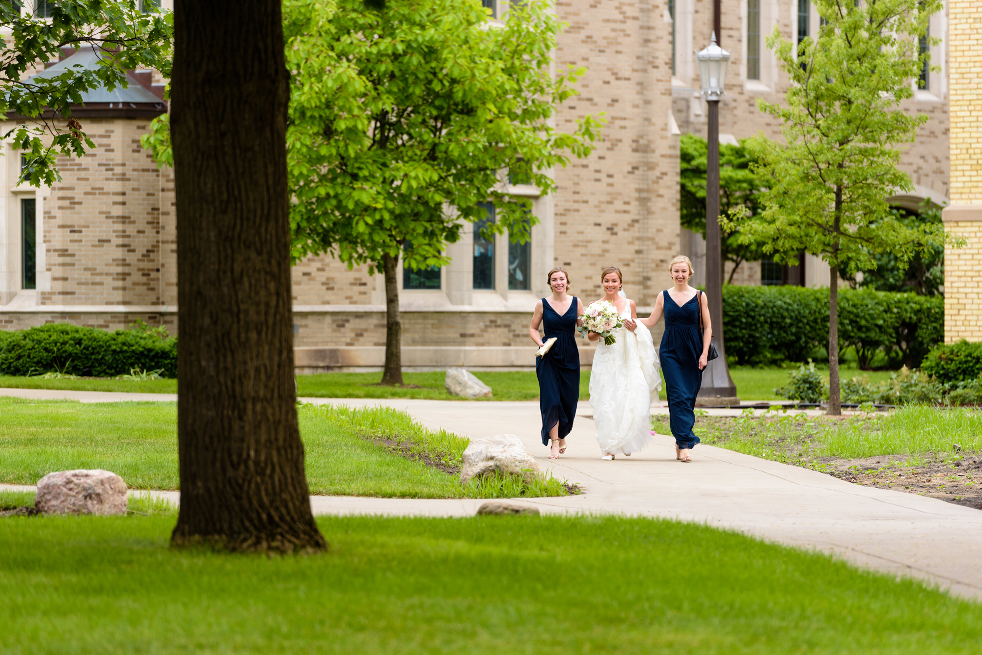 Bride walking with her sisters to her first look with her groom before their wedding ceremony at the Basilica of the Sacred Heart on the campus of the University of Notre Dame