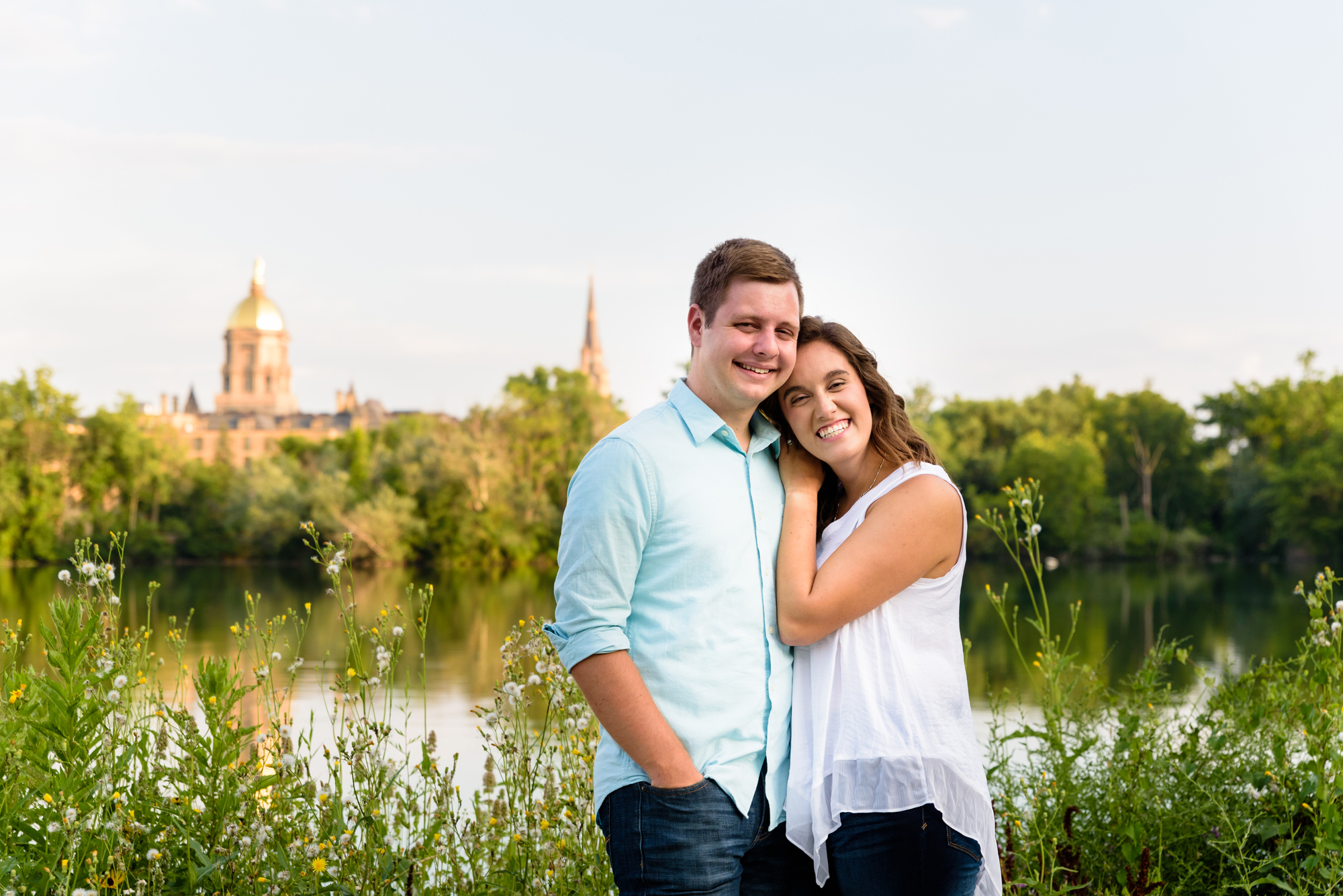 Engaged couple across St Joseph’s Lake with the Basilica and Dome in the background on the campus of the University of Notre Dame