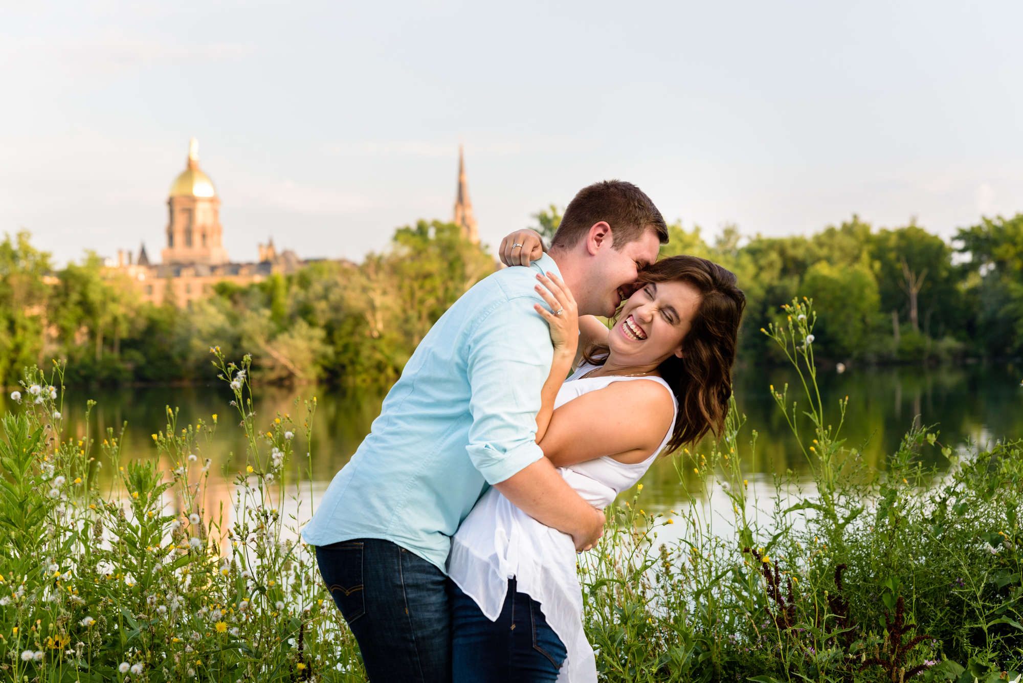 Engaged couple across St Joseph’s Lake with the Basilica and Dome in the background on the campus of the University of Notre Dame