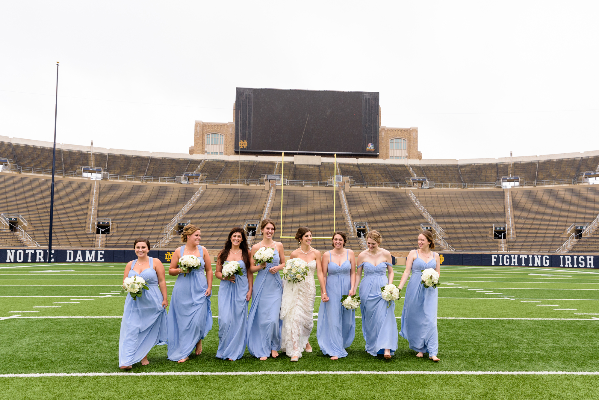 Bridesmaid on Notre Dame football field after their wedding ceremony at the Basilica of the Sacred Heart on the campus of the University of Notre Dame