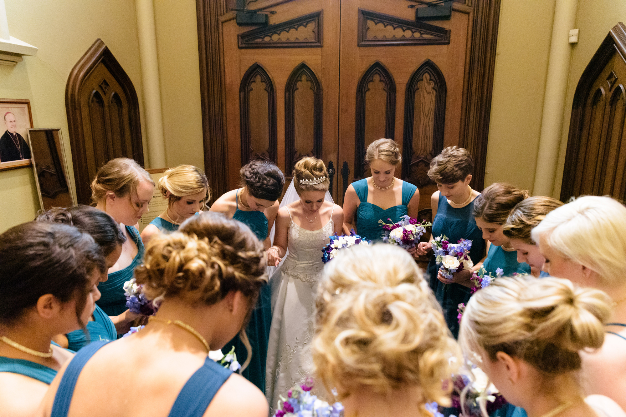 Bride praying with her bridesmaids before their wedding ceremony at the Basilica of the Sacred Heart on the campus of the University of Notre Dame